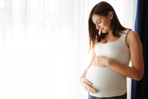 Portret szczęśliwej kobiety w ciąży dotykającej brzucha
