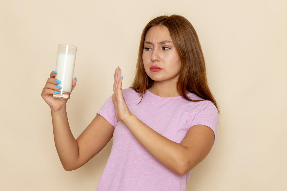 Widok z przodu młoda atrakcyjna kobieta w różowej koszulce i niebieskich dżinsach trzyma szklankę mleka
