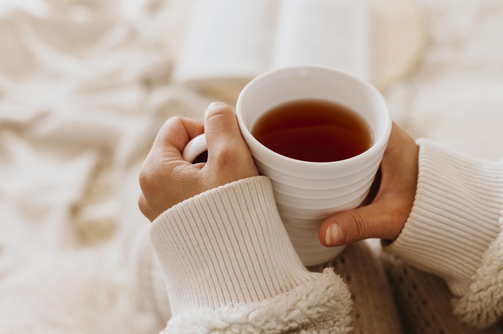 młoda kobieta trzyma filiżankę herbaty, ciesząc się ferie zimowe