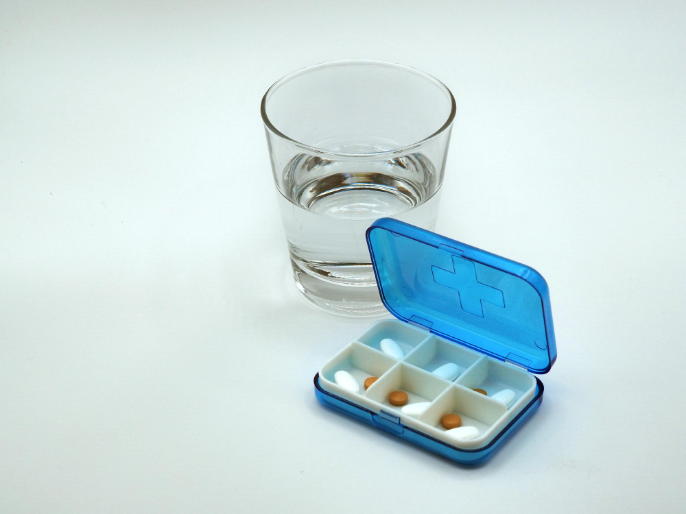 pudełko na leki i szklanka wody na białym tle