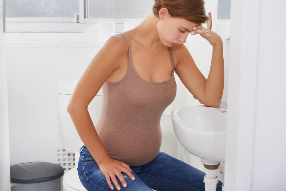 kobieta w ciąży siedząca na toalecie