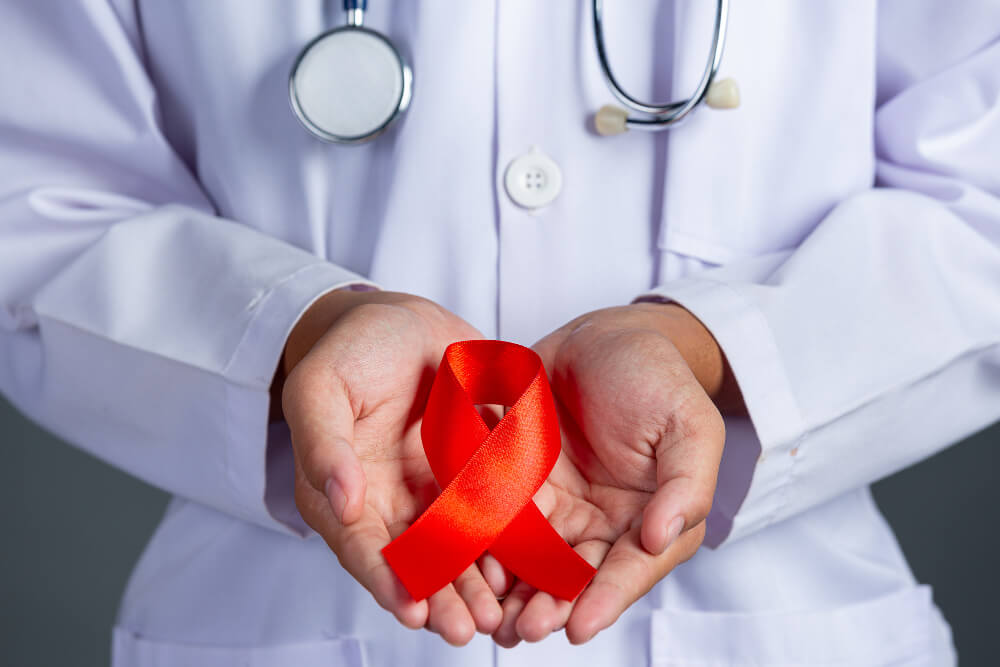 lekarz trzymający w dłoniach czerwoną kokardę – symbol solidarności z osobami zakażonymi HIV